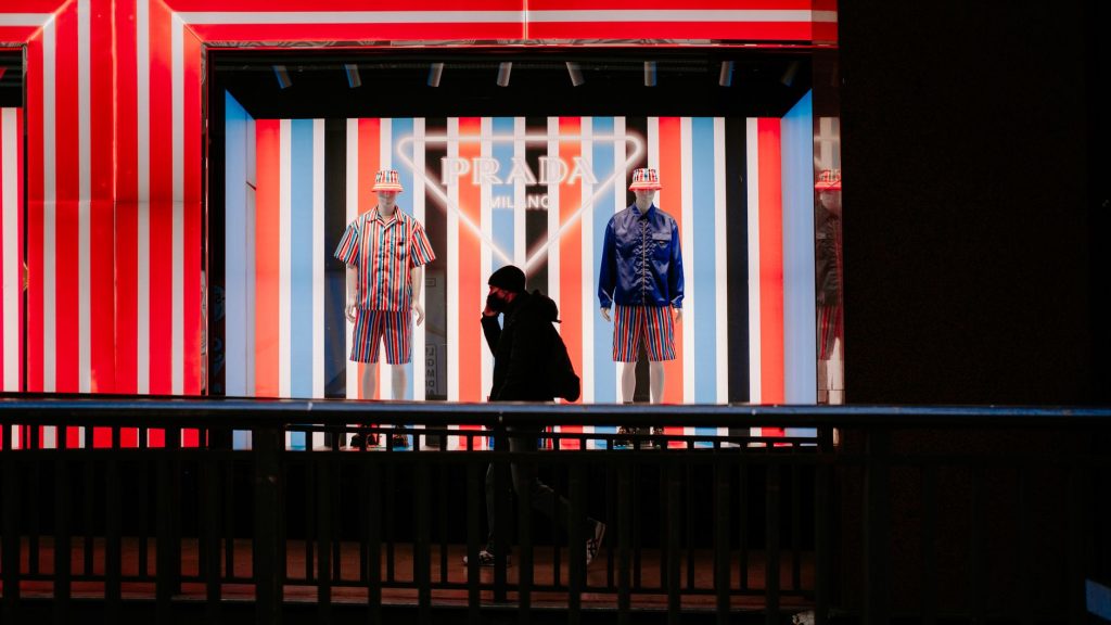 Un homme passe devant une vitrine colorée ornée de mannequins et de rayures vives.